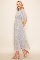 woman wearing a light blue floral midi dress with puff sleeves and a tiered skirt, paired with strappy heels