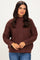woman wearing a brown cable knit sweater with a high neckline and relaxed fit, paired with blue jeans