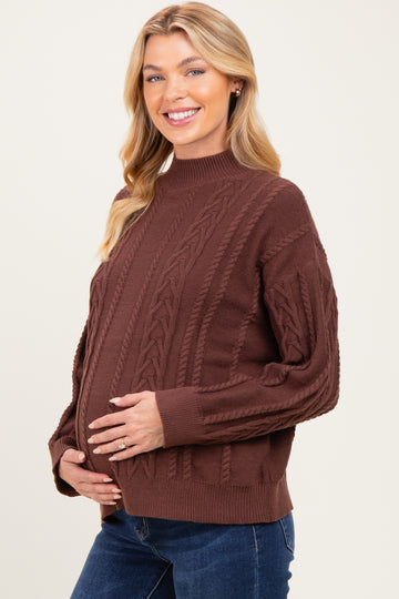 woman wearing a brown cable knit maternity sweater and holding her baby bump
