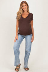 woman wearing a brown short sleeve maternity top and distressed light wash jeans, showing her baby bump