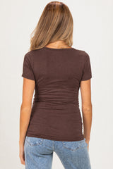 woman wearing a brown short sleeve maternity top with a fitted design, showing gathered detail at the back