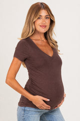 woman wearing a brown v-neck maternity top and holding her baby bump