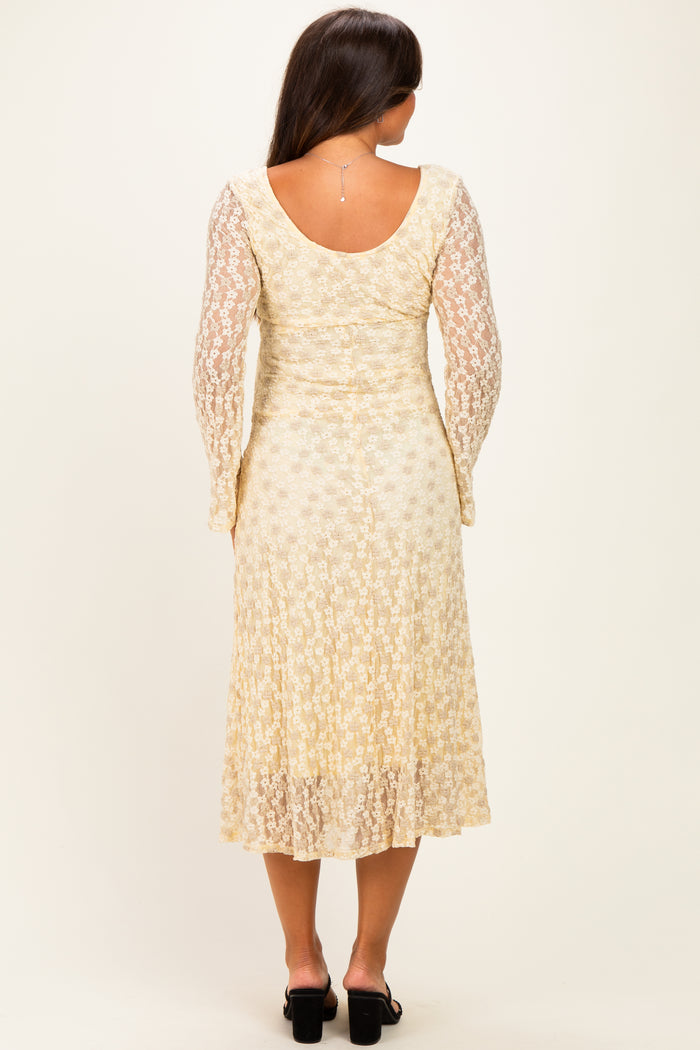 woman wearing a cream floral lace maternity dress with long sleeves and a flowing skirt from a rear view