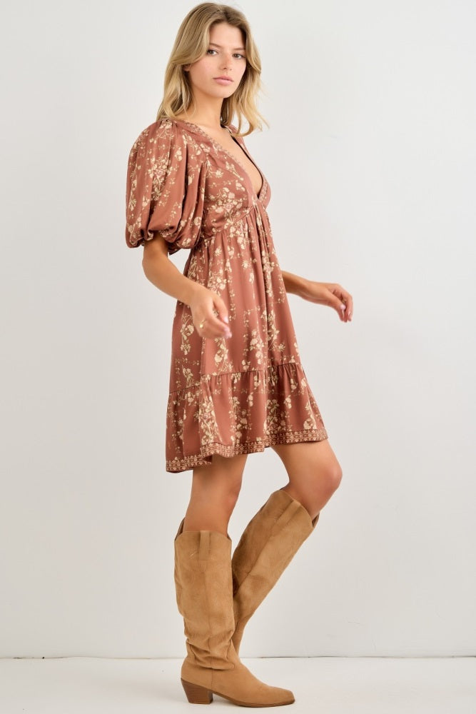 woman wearing a rust floral print puff sleeve mini dress and tan knee-high boots