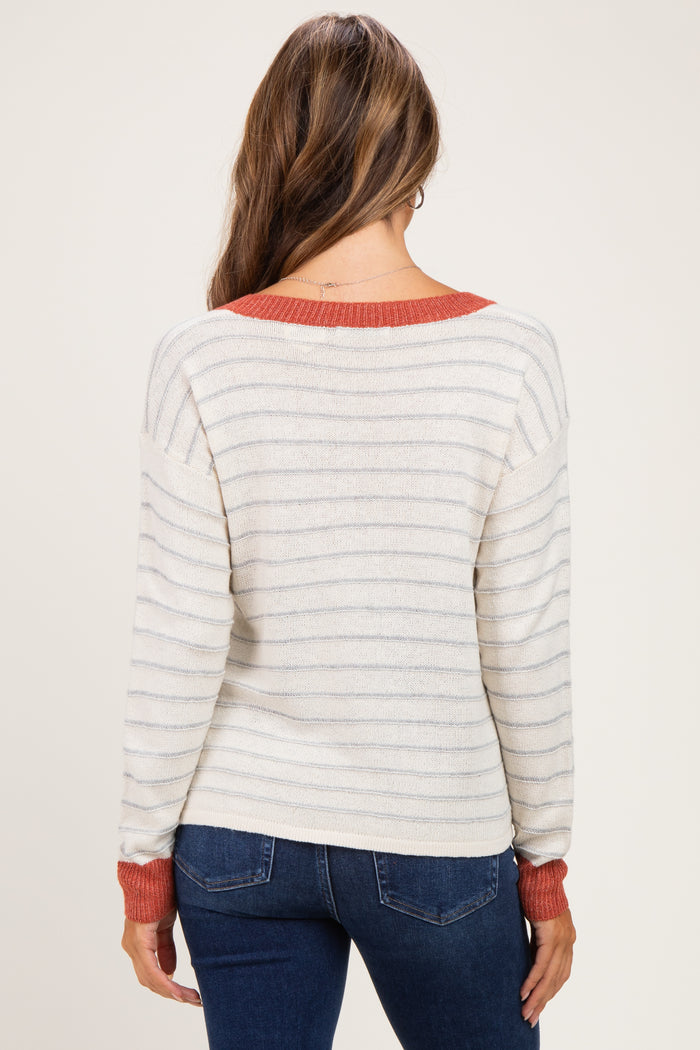 woman wearing a cream and striped maternity sweater with red accents, showing a relaxed fit from the back