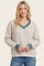 woman wearing a cream striped sweater with a v-neck and teal trim, styled with blue jeans