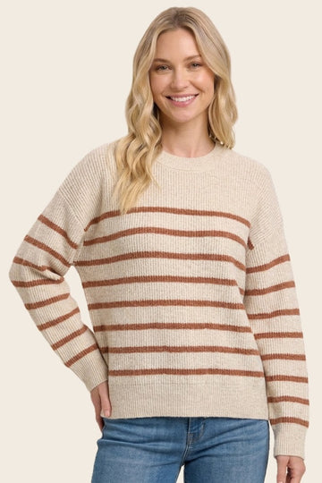woman wearing a beige striped sweater with rust-colored stripes and relaxed fit, smiling at the camera