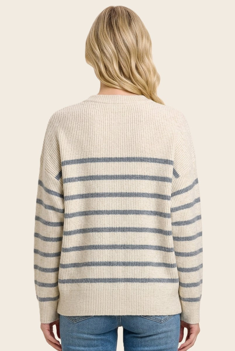 woman wearing a cream oversized sweater with blue stripes, view from the back, paired with light blue jeans