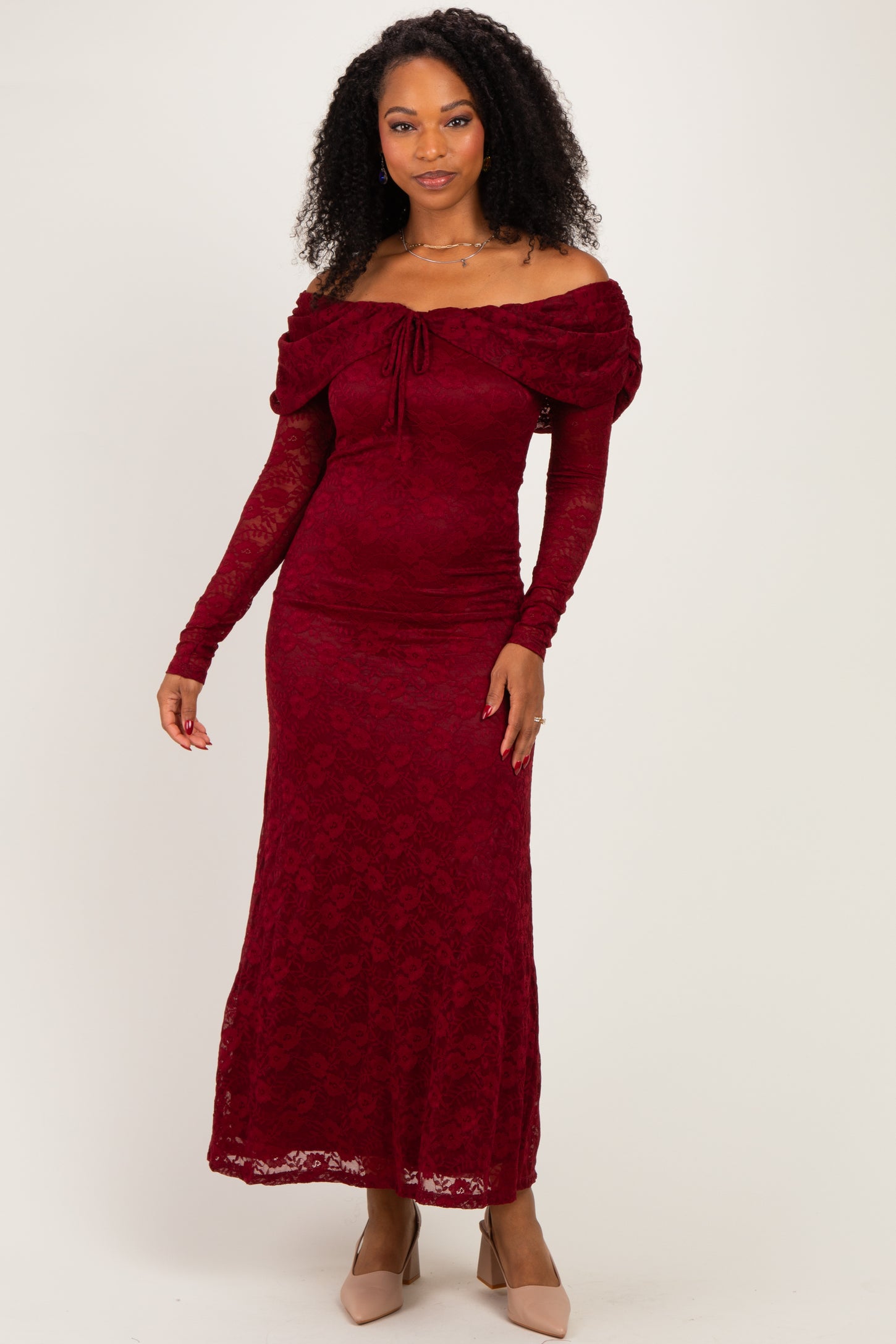woman wearing a burgundy off-shoulder lace maxi dress with long sleeves and a fitted silhouette