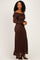 woman wearing a brown off-the-shoulder lace maxi dress with a fitted silhouette and long sleeves