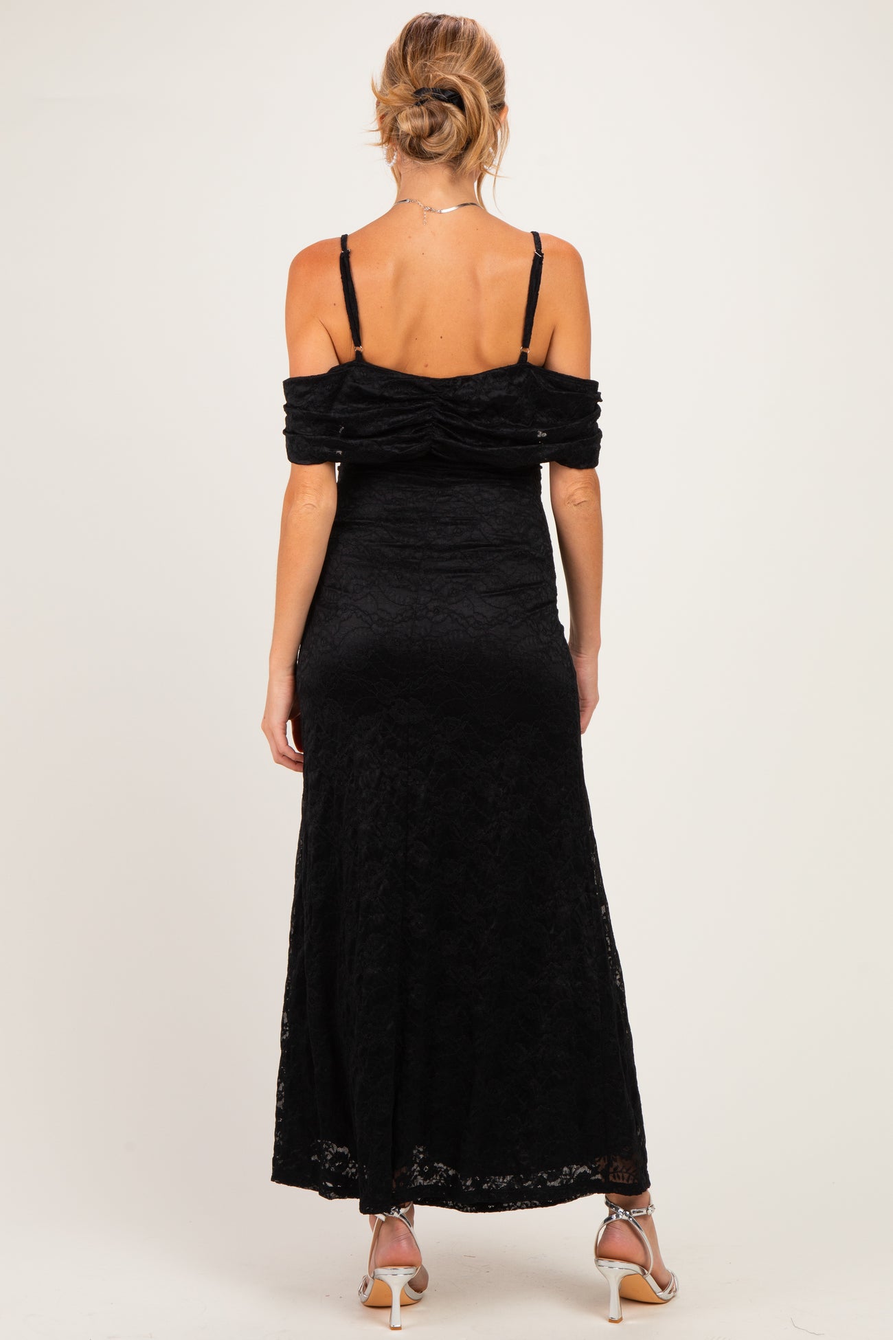 woman wearing a black off-the-shoulder lace maternity dress, showing a fitted silhouette from the back