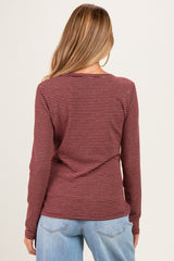 woman wearing a maroon and black striped maternity top with long sleeves, showing the back view