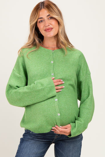 woman wearing a green maternity cardigan and holding her baby bump