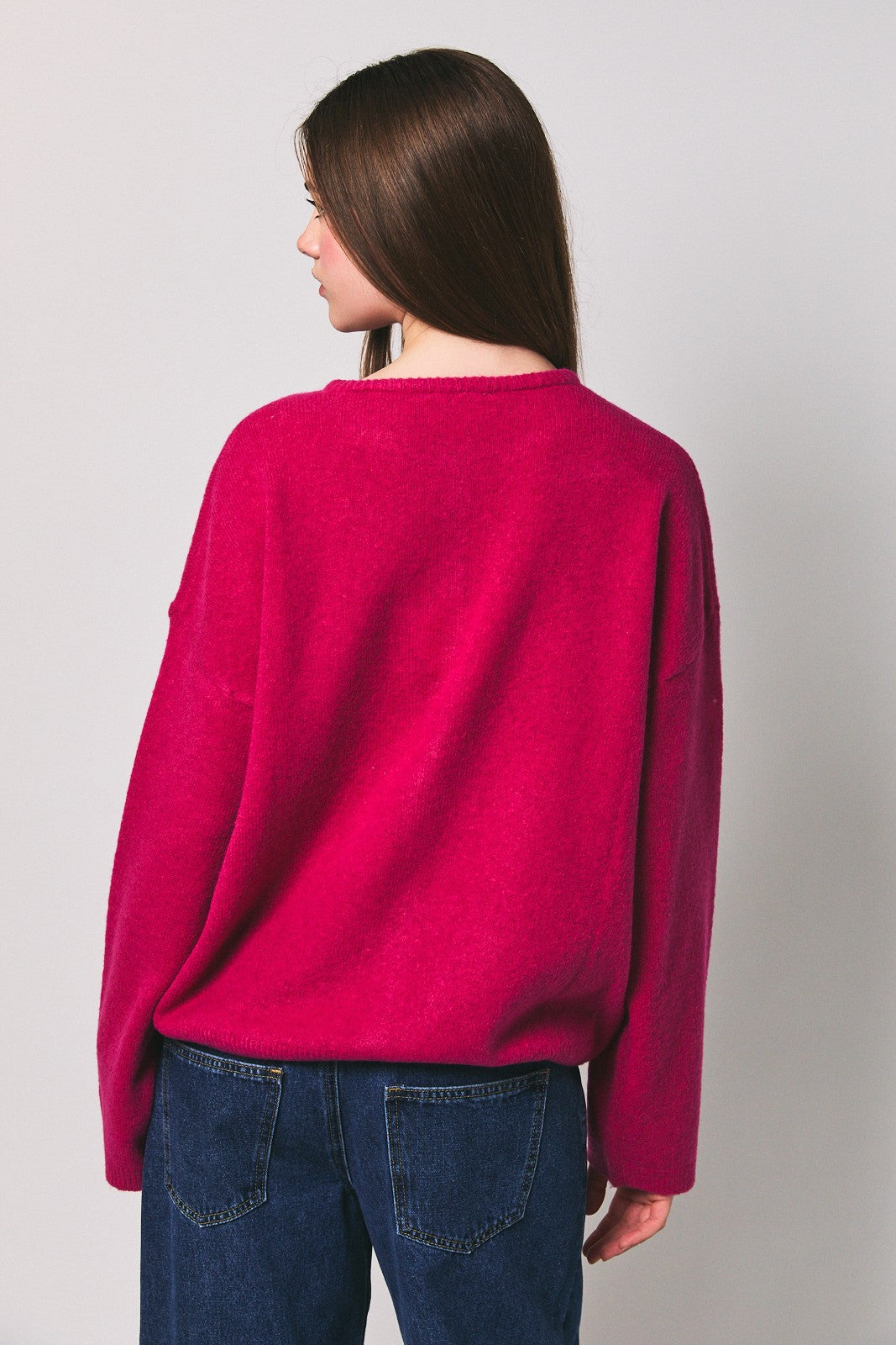 woman wearing a bright pink oversized sweater with a relaxed fit, viewed from the back