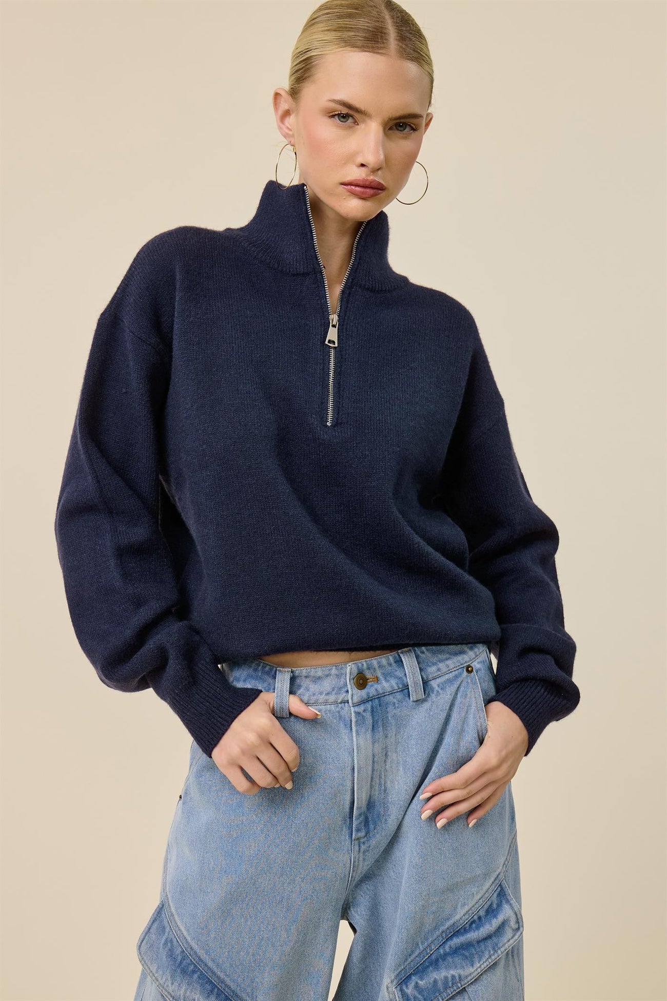 woman wearing a navy blue half-zip pullover sweater with balloon sleeves and high-waisted denim wide-leg jeans