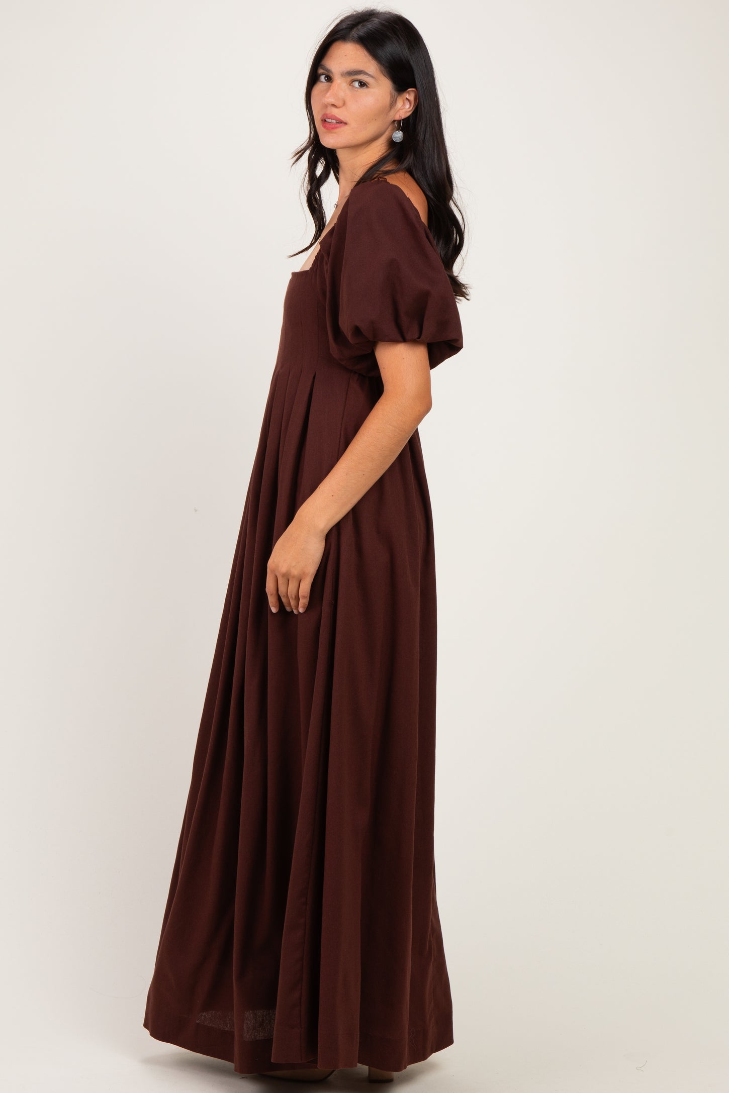 woman wearing a brown puff sleeve maxi dress with a fitted bodice and flowing skirt, shown from the side