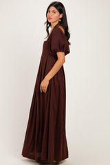 woman wearing a brown puff sleeve maxi dress with a fitted bodice and flowing skirt, shown from the side