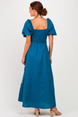 woman wearing a teal maxi dress with puff sleeves and a smocked bodice, seen from the back