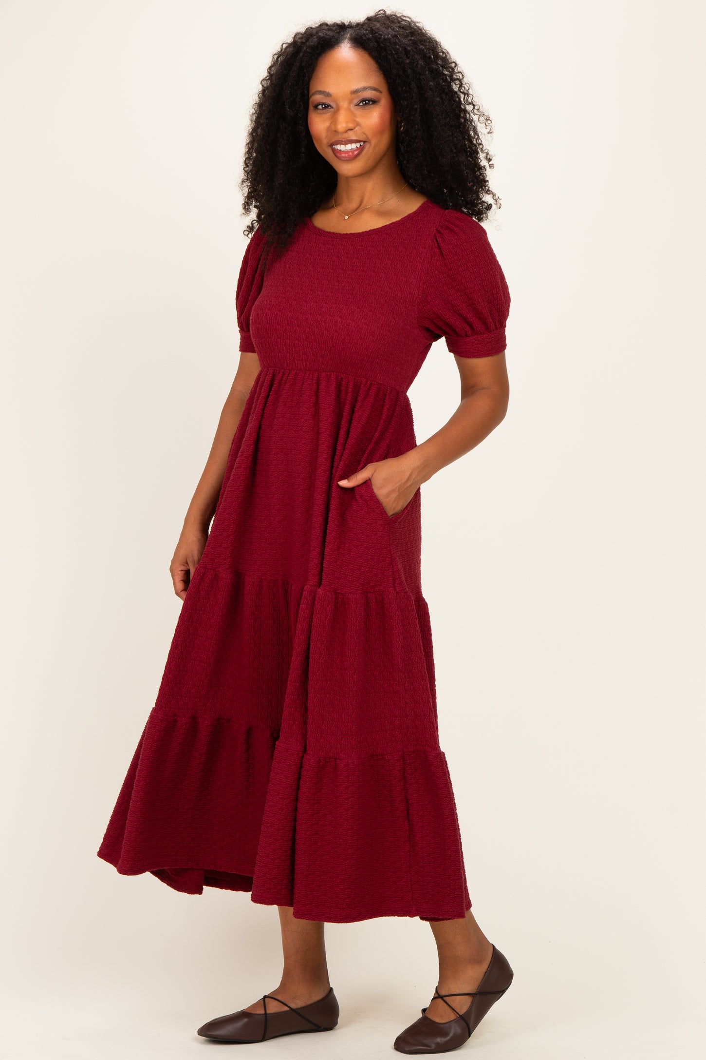 woman wearing a burgundy tiered maxi dress with short puff sleeves and side pockets