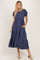 woman wearing a navy blue tiered midi dress with puff sleeves and side pockets, standing in a light pose