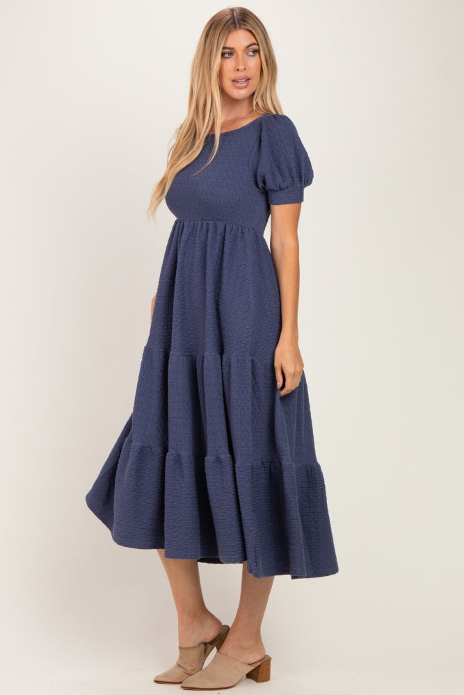 woman wearing a navy blue puff sleeve maxi dress with a tiered skirt and a relaxed fit