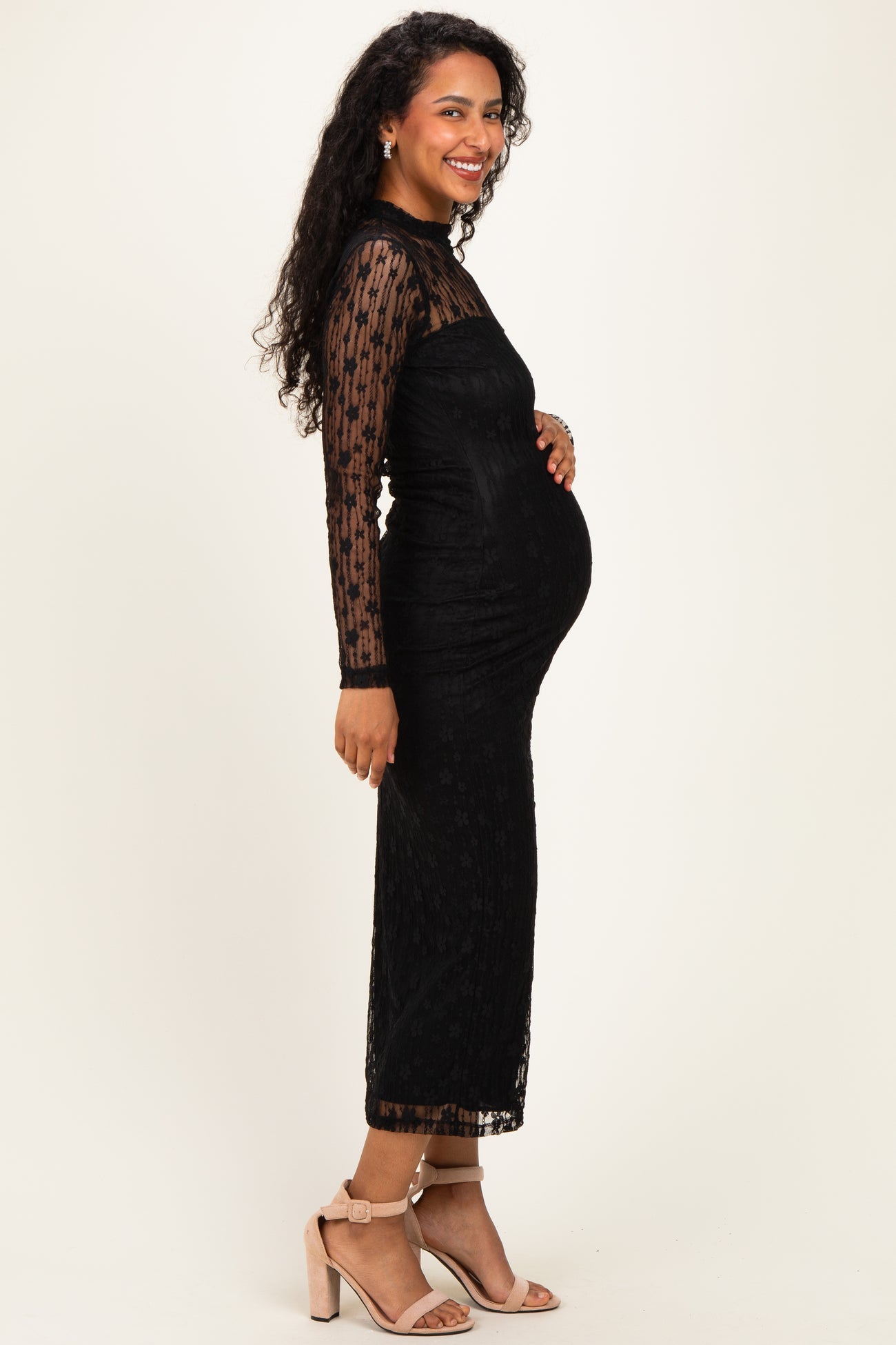 woman wearing a black lace long sleeve maternity dress and holding her baby bump