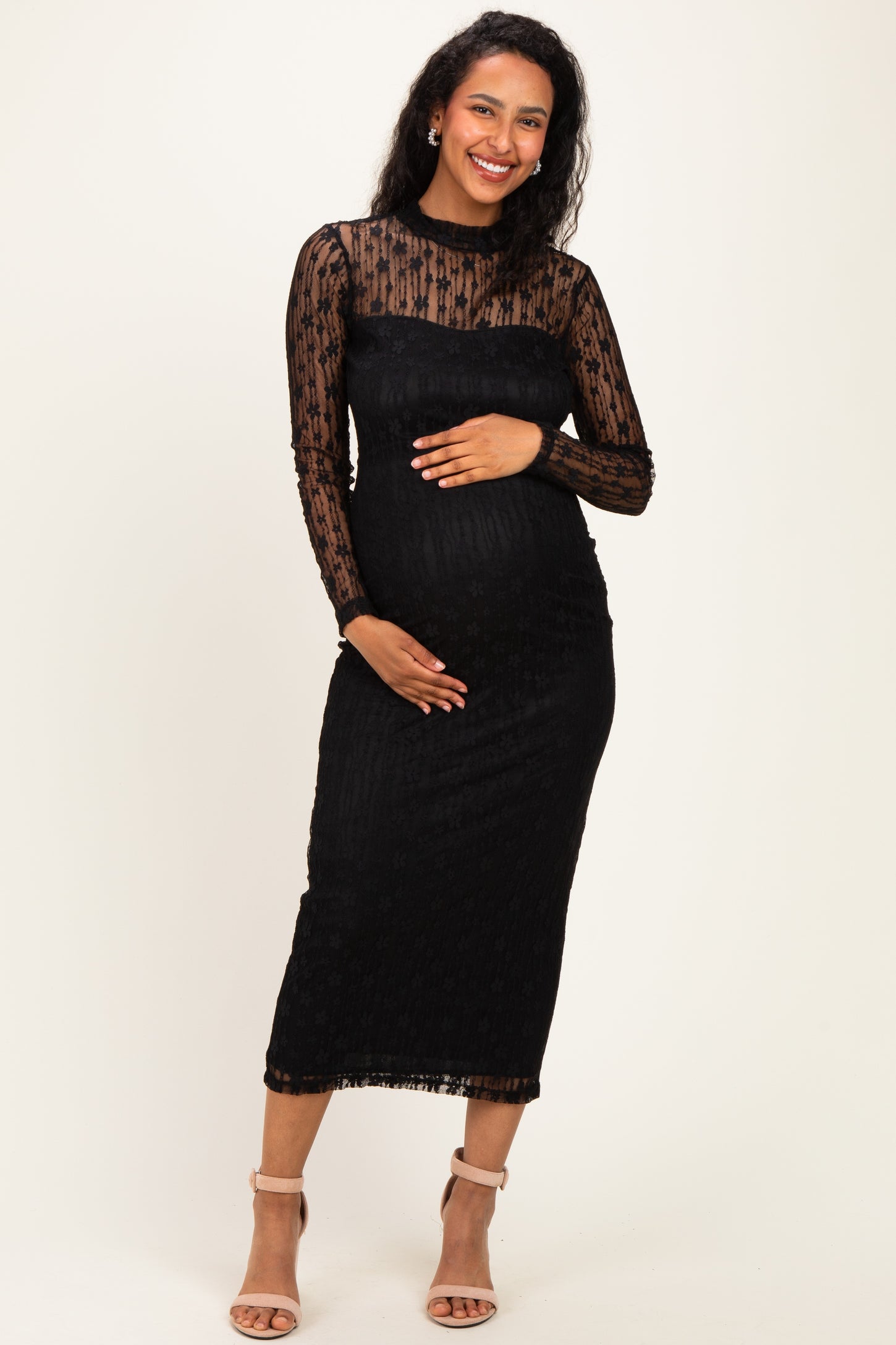 woman wearing a black long sleeve lace maternity dress and holding her baby bump