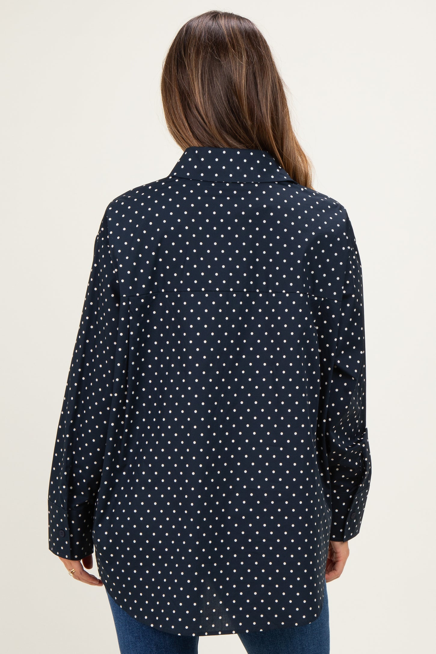 woman wearing a black and white polka dot maternity shirt with a relaxed fit, showing the back view