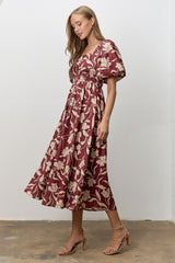 woman wearing a burgundy floral midi dress with puff sleeves and a fitted bodice