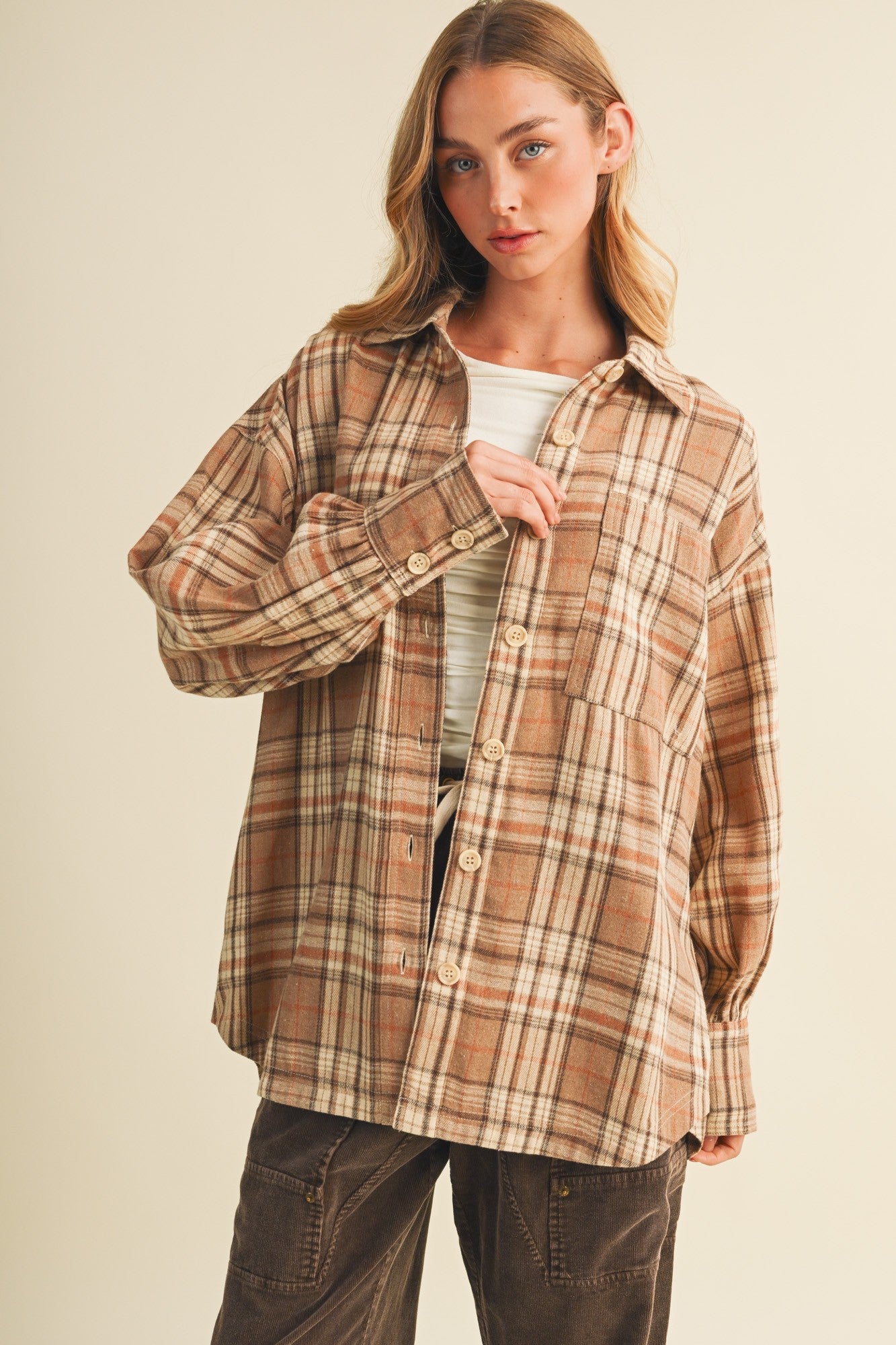 woman wearing a brown plaid oversized button-up shirt with buttons and a relaxed fit