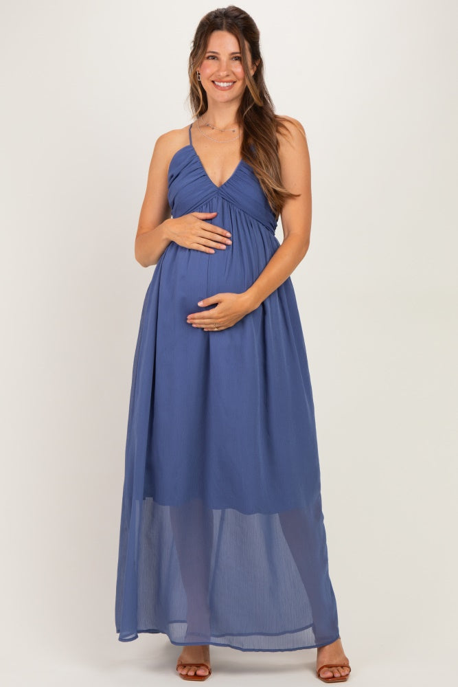 woman wearing a blue maternity maxi dress with a flowy skirt and empire waist, showing her baby bump