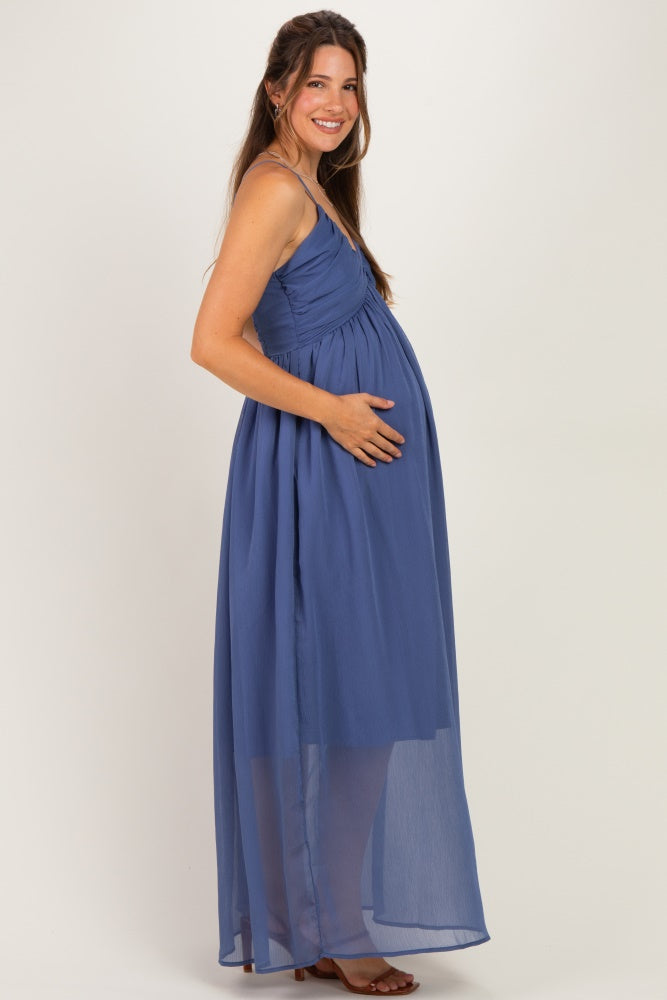 woman wearing a flowy blue maternity maxi dress with a ruched bodice and showcasing her baby bump