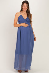 woman wearing a navy blue maternity maxi dress with spaghetti straps and a ruched bodice, holding her baby bump