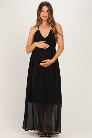 woman wearing a black maternity maxi dress with spaghetti straps and holding her baby bump