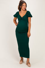 woman wearing a green maternity dress with puff sleeves and a ruched design, showing her baby bump