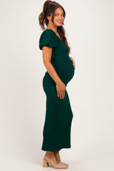 woman wearing a green maternity dress with puff sleeves and ruching, showing off her baby bump