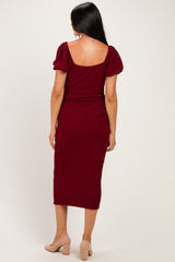 woman wearing a burgundy midi dress with puff sleeves and a fitted silhouette, shown from the back