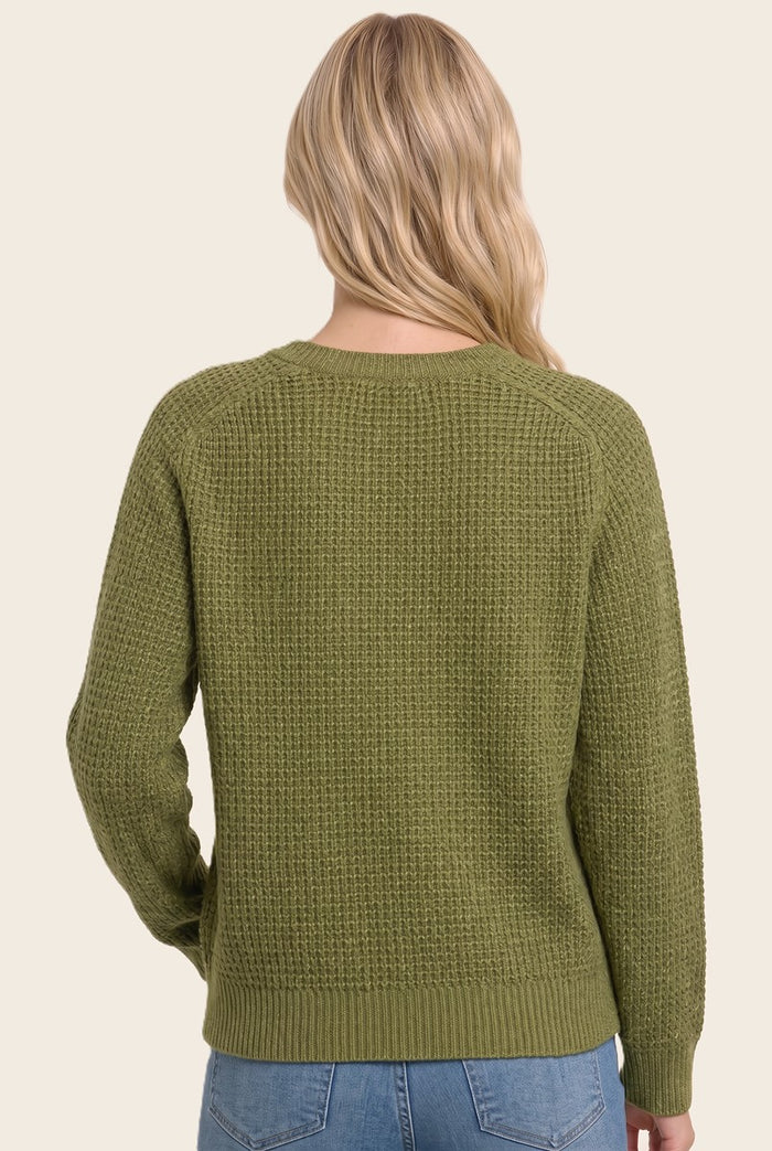 woman wearing a green textured knit sweater, shown from the back, styled with light blue jeans