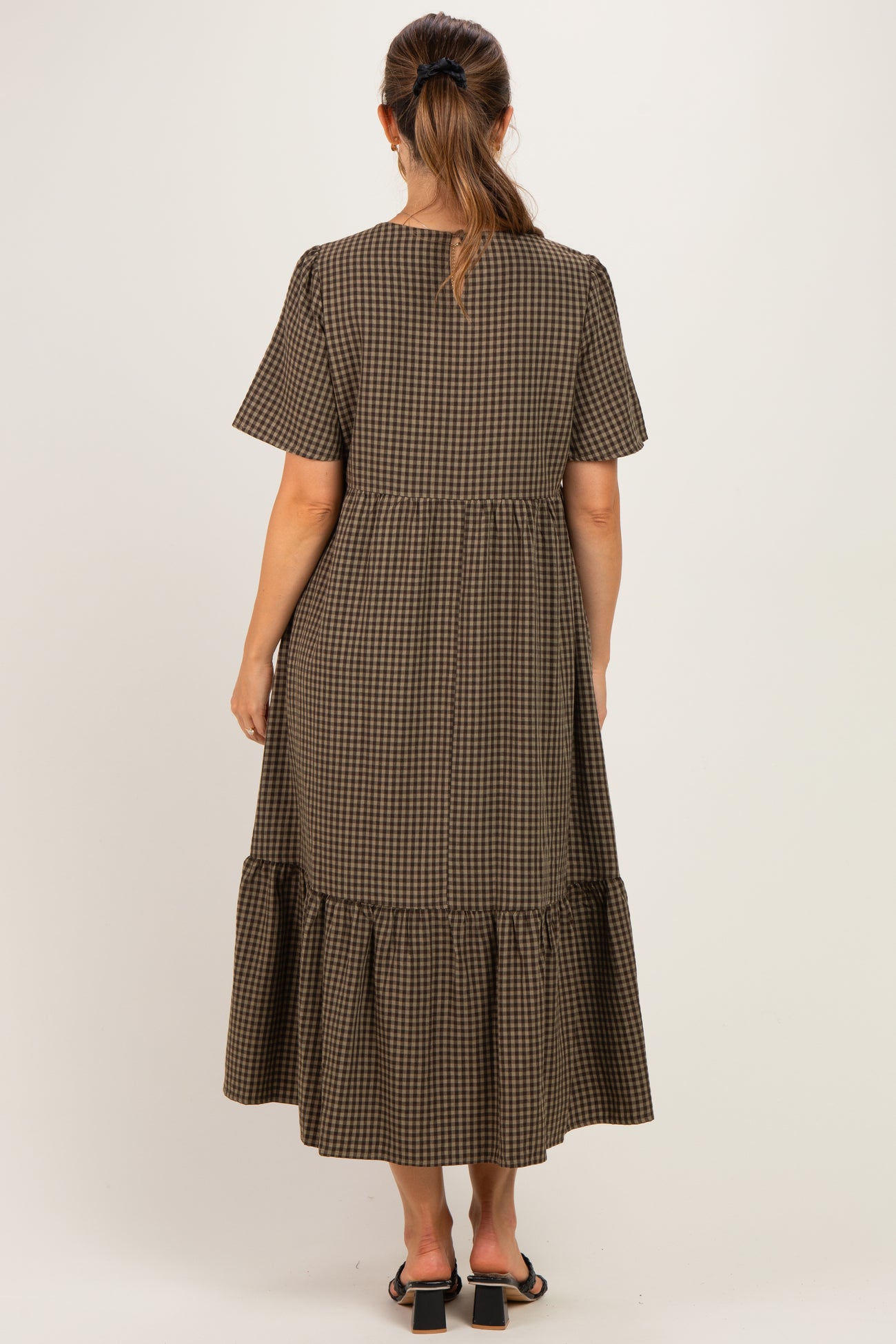 woman wearing a brown checkered maternity maxi dress with short sleeves and a tiered ruffle hem