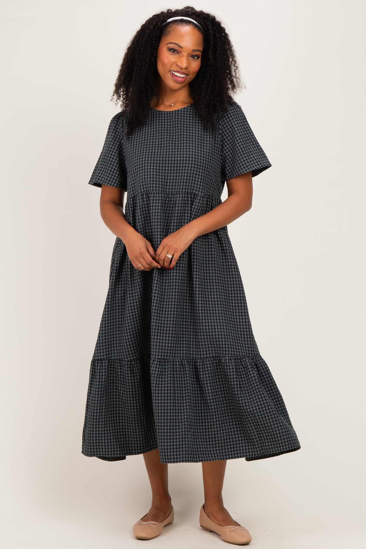 woman wearing a black and white gingham tiered midi dress with short sleeves and a relaxed fit