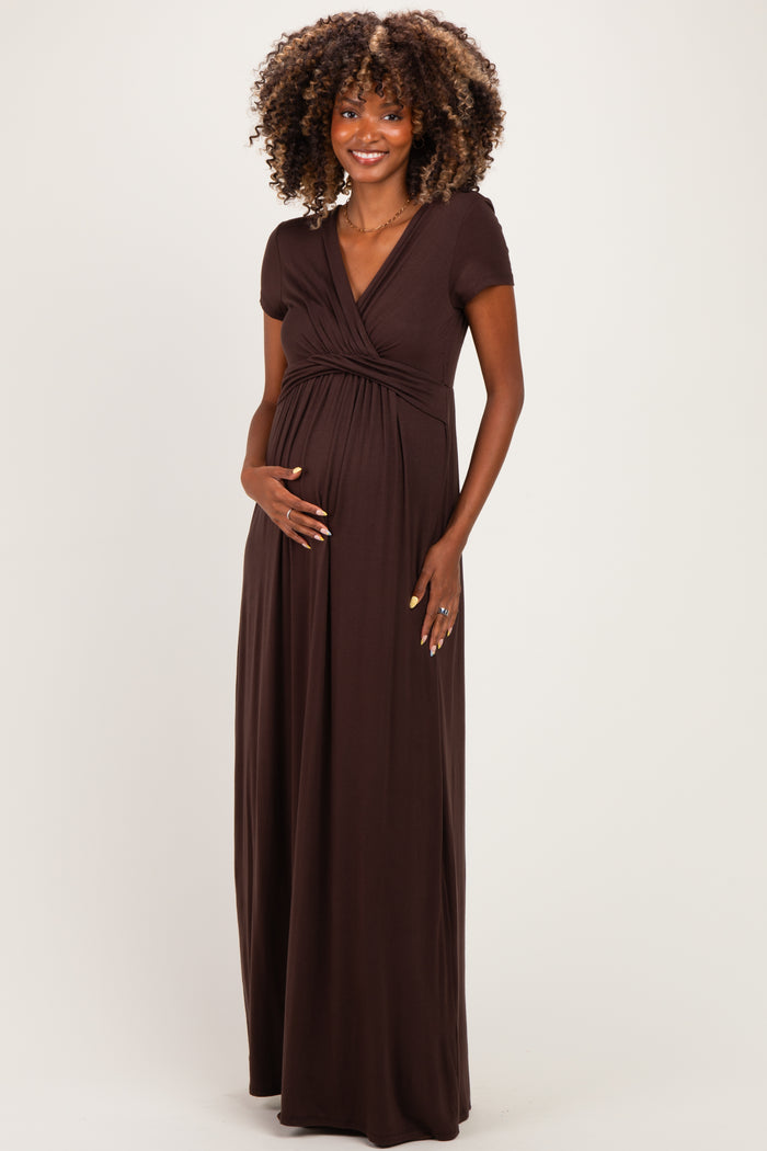 woman wearing a chocolate brown short sleeve maternity maxi dress and holding her baby bump