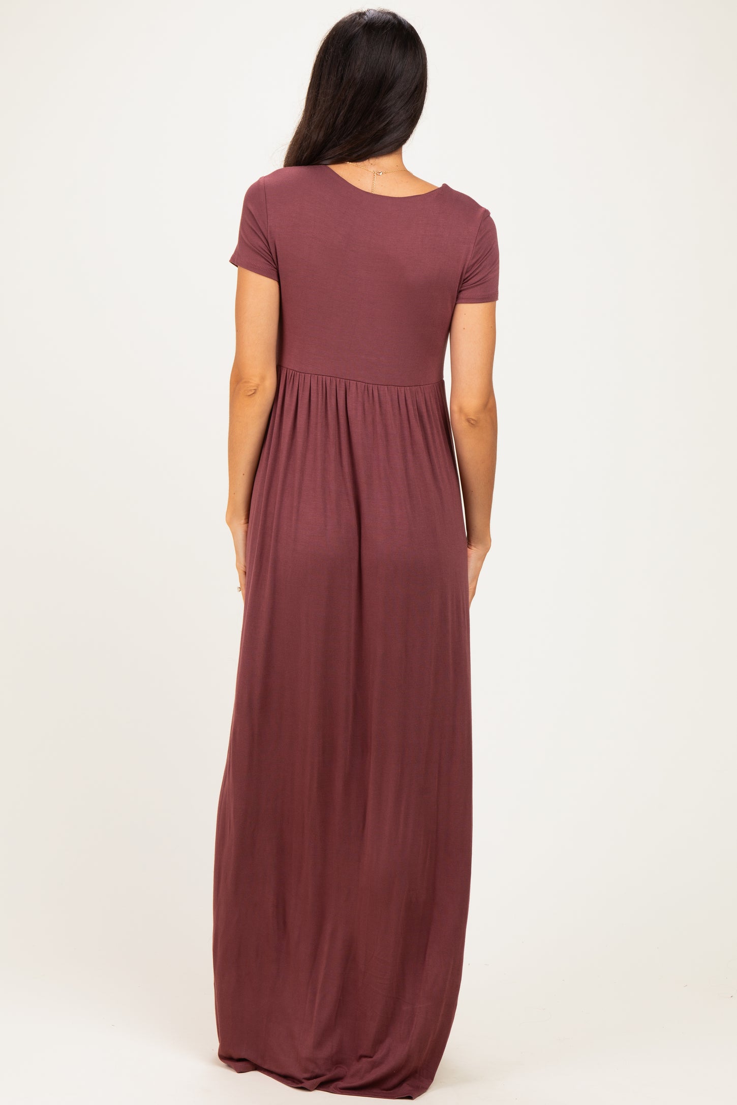 woman wearing a burgundy short sleeve maxi dress with a fitted bodice and flowy skirt from the back