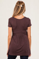 woman wearing a dark mauve short sleeve maternity top with a gathered waist and relaxed fit, seen from the back