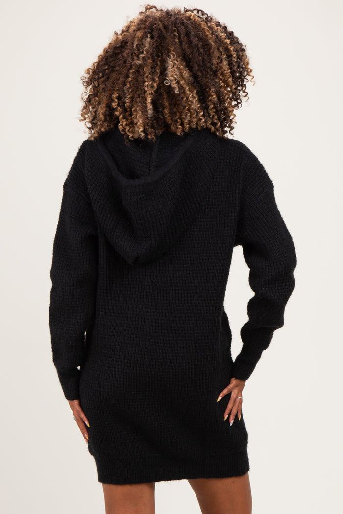 woman wearing a black knitted maternity hoodie dress, showing a relaxed fit and hood in the back