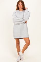 woman wearing a gray oversized sweatshirt dress with balloon sleeves and white sneakers