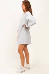 woman wearing a gray oversized sweatshirt dress with a v-neck and long sleeves, standing in side profile