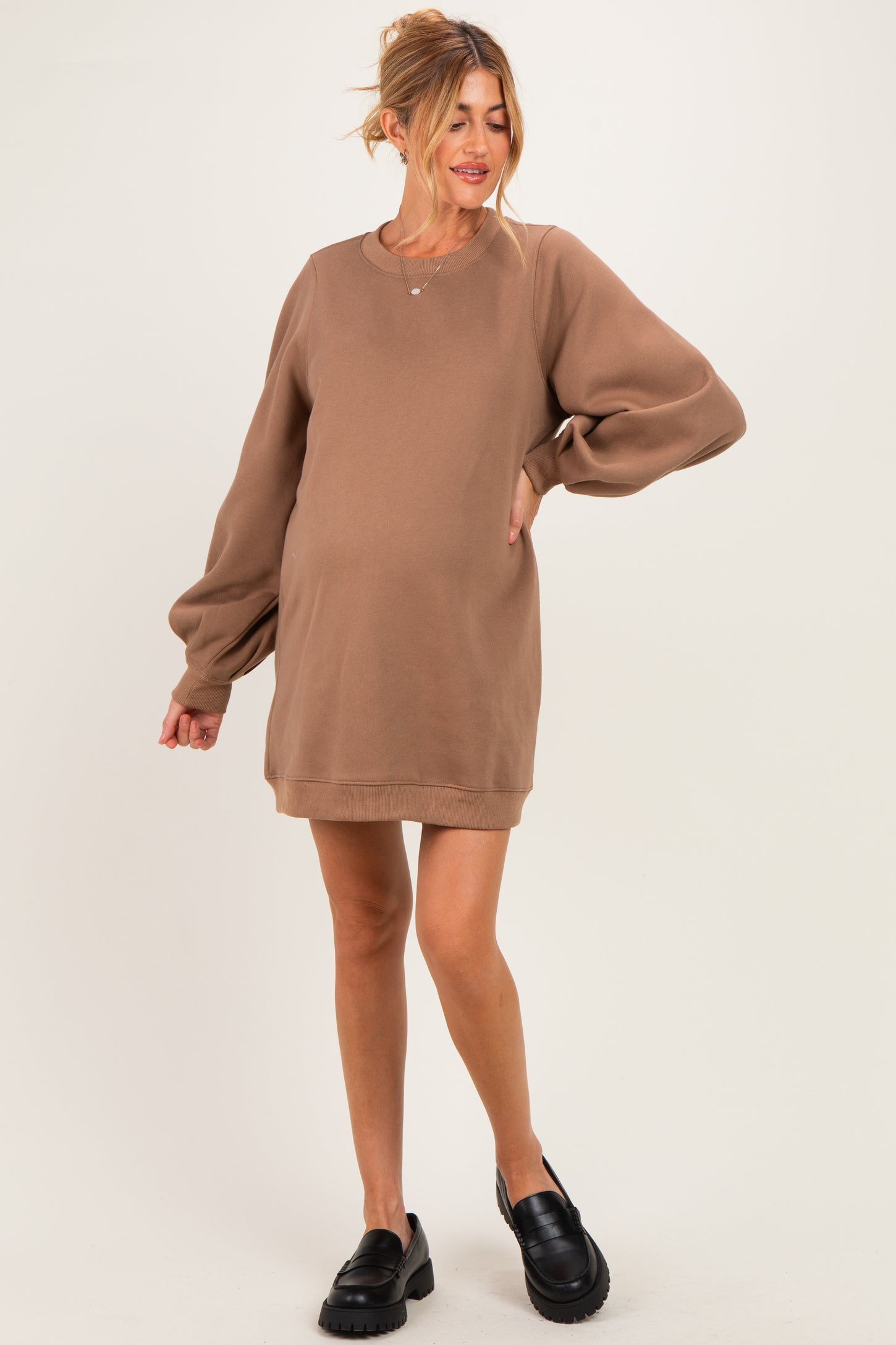 woman wearing a brown maternity sweatshirt dress with long puff sleeves and a visible baby bump