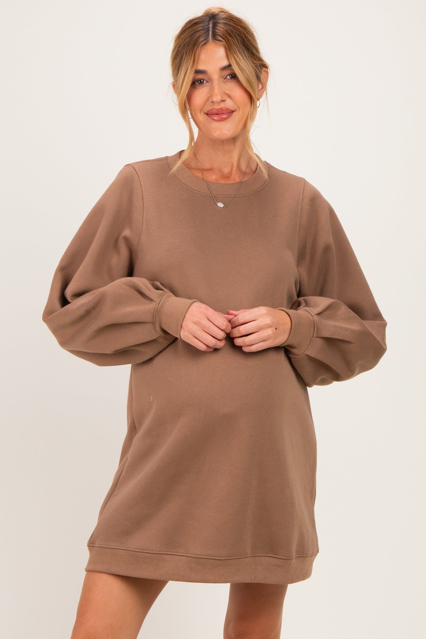 woman wearing a brown maternity sweatshirt dress with puff sleeves and a visible baby bump