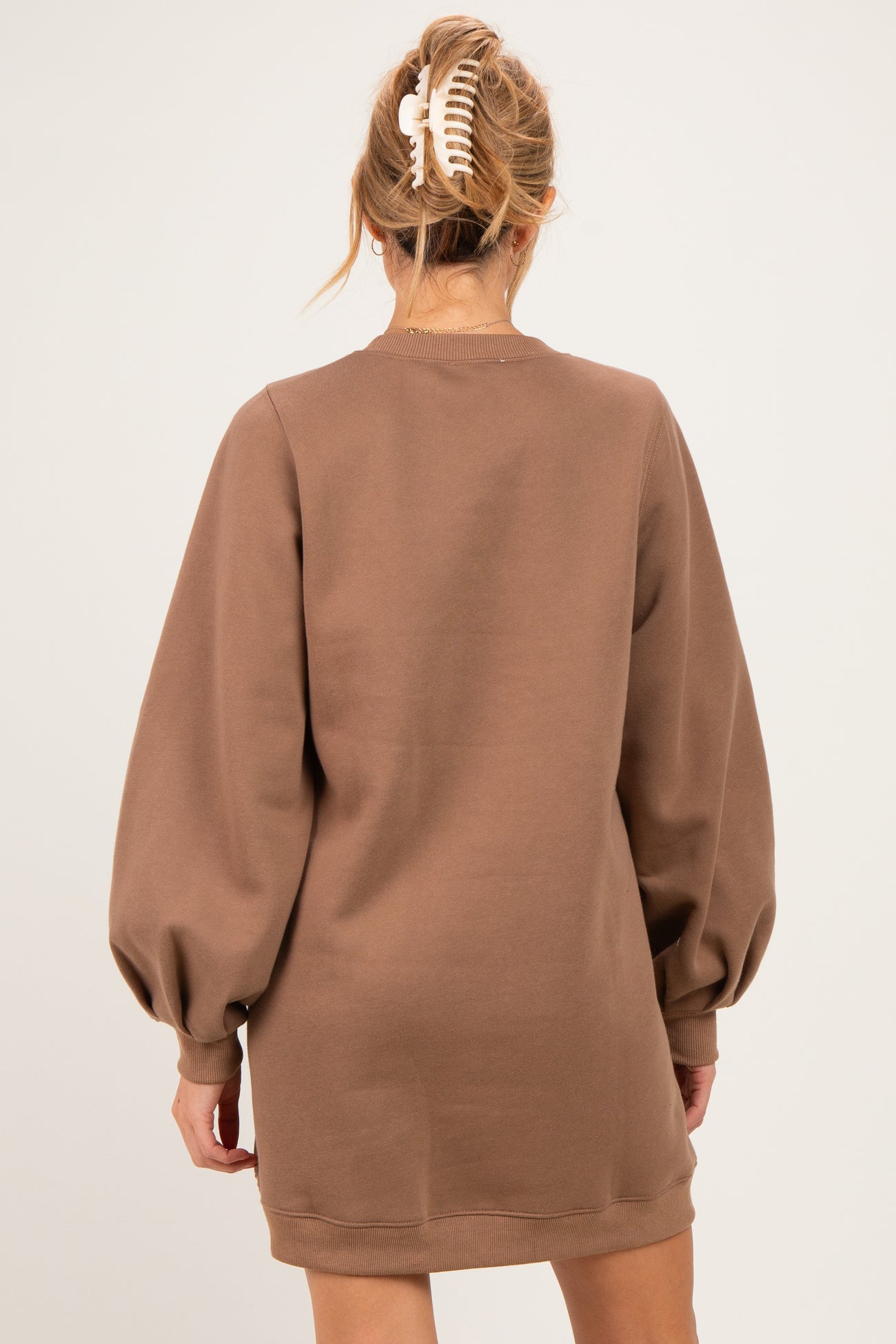 woman wearing a brown maternity sweatshirt dress with puffed sleeves, showing the back view