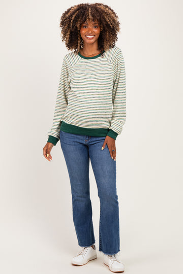 woman wearing a green and striped maternity sweatshirt with a relaxed fit paired with blue jeans and white sneakers
